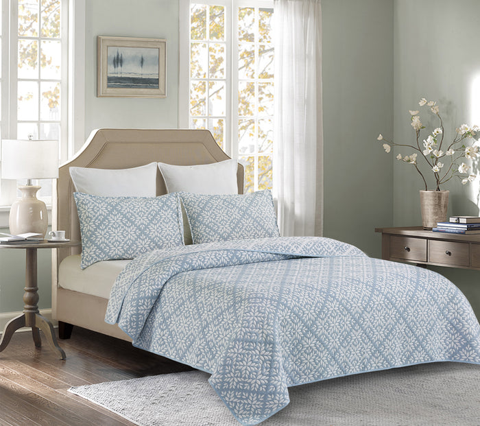 A Blue Leaves Coverlet Set displayed on a bed.