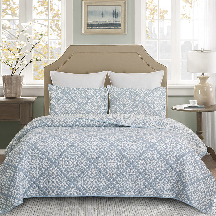 A Blue Leaves Coverlet Set displayed on a bed.