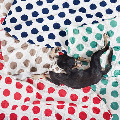 A dot pet quilt displayed on a made bed.