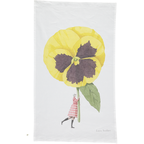 A white tea towel featuring a whimsical illustration of a small woman holding a gigantic yelllow pansy by the stem. Art by Laura Stoddart.