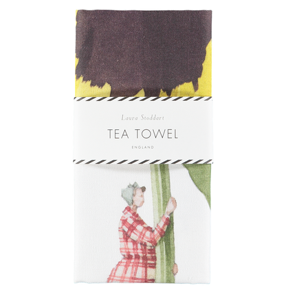 The Laura Stoddart Tea Towel in retail packaging, neatly folded with a white paper belly band.