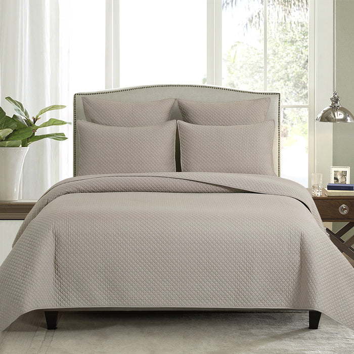 A Kya Quilt Set displayed on a made bed.