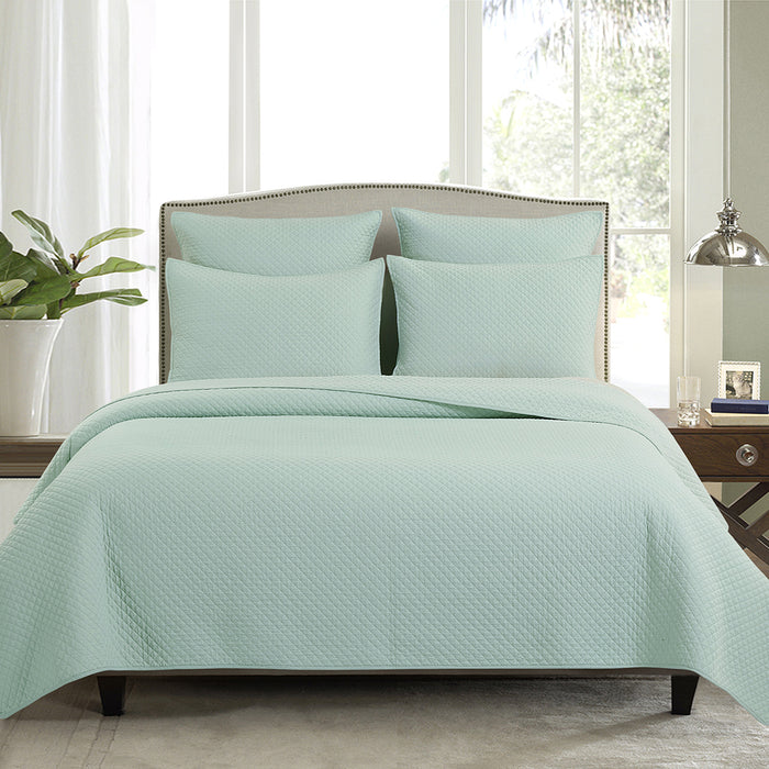 A Kya Quilt Set displayed on a made bed.