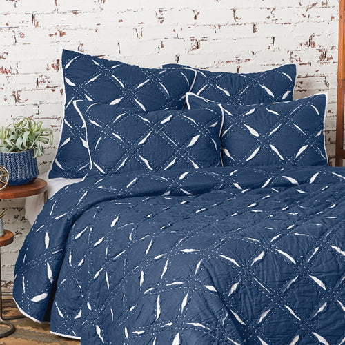 A parker indigo quilt displayed on a made bed.