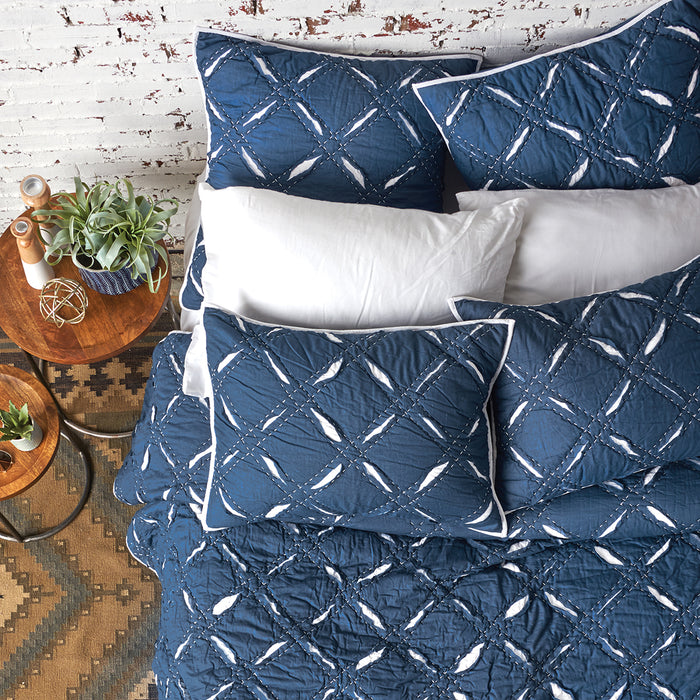 A parker indigo quilt displayed on a made bed.