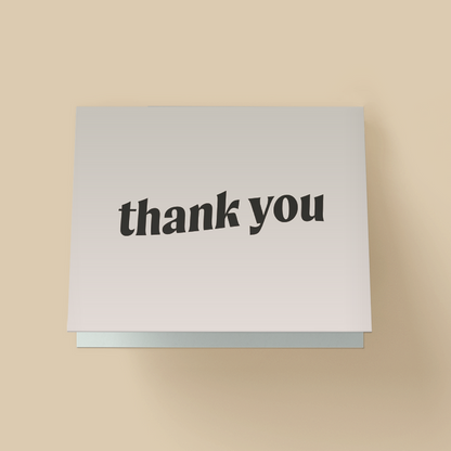 Minimalist thank you card with a white background. The words "thank you" are in bold, black, lowercase, wavy serif font, slightly tilted in the center.