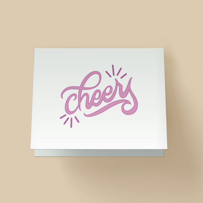 Minimalist greeting card with white background. The word 'cheers' is in large purple, brush script lettering in the center, with small purple starburst accents on the top right and bottom left.